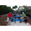 A Man and a Woman Sitting on the Chow Hound Table (Blue) While Petting a Dog 